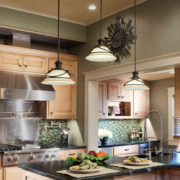 Specialty Products task lighting pendants over eating space in kitchen with green glass backsplash and light cabinets | Marchand Creative Kitchens Cabinets New Orleans Metairie Mandeville LA