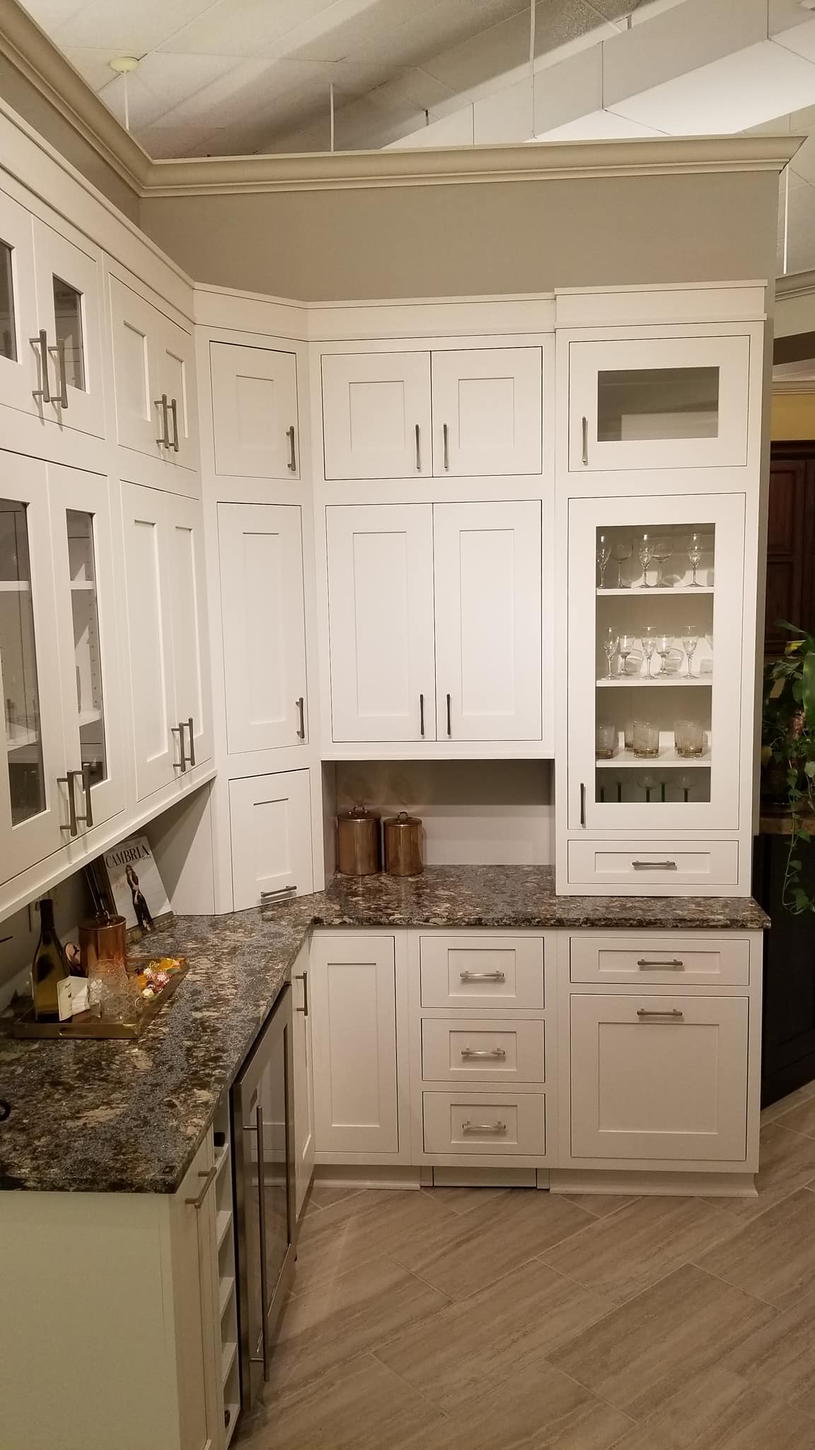 showroom cabinets display of glass front and white cabinets, wine cooler, granite countertop | Marchand Creative Kitchens Cabinets New Orleans Metairie Mandeville LA